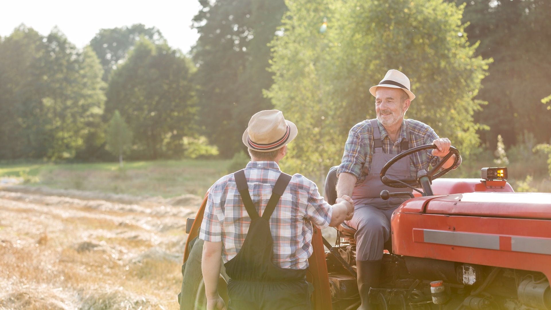 two men shaking hands, one is on a tractor